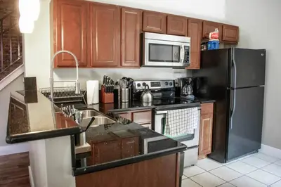 a kitchen with wooden cabinets and a black refrigerator at Huge Parkside Retreat - Private Roof Decks in Cincinnati
