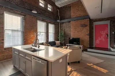a kitchen with a sink and a living room at Entire Historic Building Sleeps 30 in Cincinnati