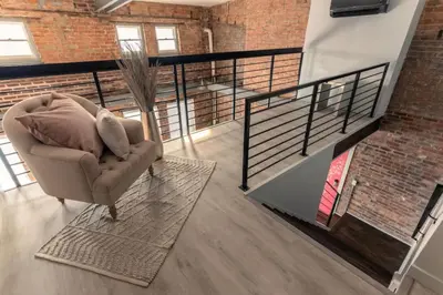 a living room with a chair and a staircase at Entire Historic Building Sleeps 30 in Cincinnati