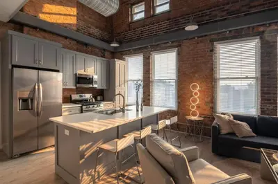a kitchen and living room with a brick wall at BUBBLES FANTASY SUITE Explore OTR and Rhinegeist in Cincinnati
