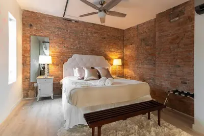 a bedroom with a large bed with a brick wall at BUBBLES FANTASY SUITE Explore OTR and Rhinegeist in Cincinnati
