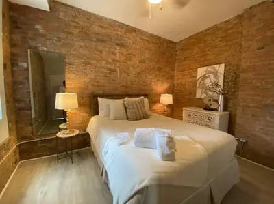 a bedroom with a large bed and a brick wall at BUBBLES FANTASY SUITE Explore OTR and Rhinegeist in Cincinnati