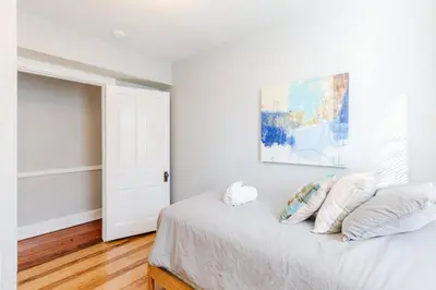 a white bedroom with a bed with pillows and a painting at Spacious Home Walk to Everything and FREE Parking in Cincinnati