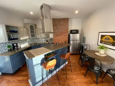 a kitchen with blue cabinets and a table and a refrigerator at OTR Penthouse Walk Everywhere FREE Parking in Cincinnati