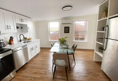 a kitchen with white cabinets and a table and a refrigerator at Explore Downtown and Mount Adams with River Views in Cincinnati