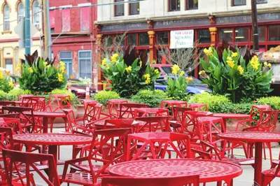 a group of red tables and chairs on a street at Over the Rhine Luxury MicroSuite On Findlay Market in Cincinnati