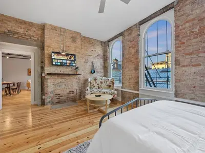 a bedroom with a brick wall and a bed and a table at Findlay Suites Explore OTR with an Outdoor Deck in Cincinnati