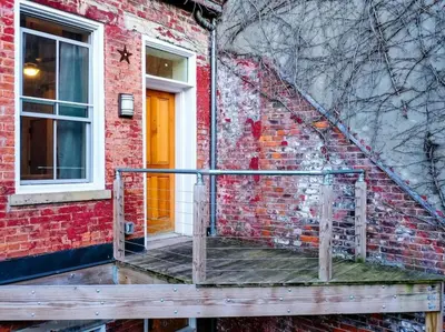 a brick building with a staircase and a yellow door at Cozy OTR Home with Private Roof Deck in Cincinnati