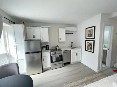 a kitchen with white cabinets and a stainless steel refrigerator at Cute Microapartment Walkable to Everything in Cincinnati