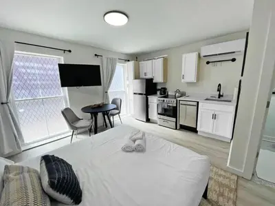 a bedroom with a white bed and a kitchen at Cute Microapartment Walkable to Everything in Cincinnati