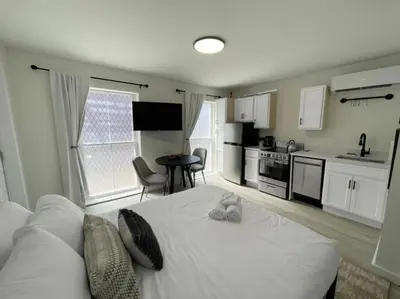 a bedroom with a white bed and a kitchen at Cute Microapartment Walkable to Everything in Cincinnati