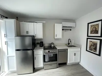 a kitchen with white cabinets and a stainless steel refrigerator at Cute Microapartment Walkable to Everything in Cincinnati