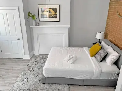 a bedroom with a bed with white sheets and yellow pillows at Quiet 1-Bedroom Loft near Entertainment District in Cincinnati