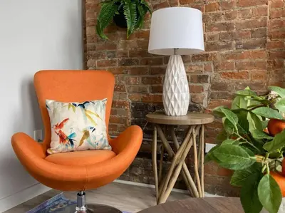a orange chair with a pillow on a table with a lamp at ZANGO Explore OTR and Downtown from a Renovated Condo in Cincinnati