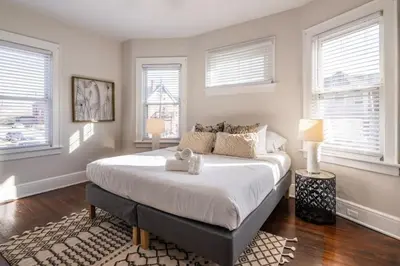 a bedroom with a large bed and two windows at Deluxe 6 Bedroom 3 Min to Downtown w 2-car Driveway in Cincinnati