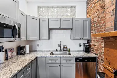 a kitchen with white cabinets and a sink and a brick wall at Loft in the heart of Over-The-Rhine in Cincinnati