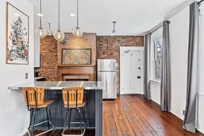 a kitchen with a counter with chairs and a refrigerator at Loft in the heart of Over-The-Rhine in Cincinnati