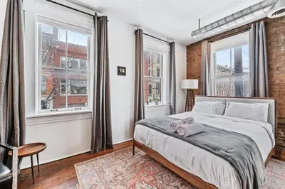a bedroom with a bed and two windows at Loft in the heart of Over-The-Rhine in Cincinnati
