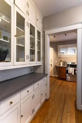 a kitchen with white cabinets and a wooden floor at Hyde Park Comfort Near Rookwood in Cincinnati