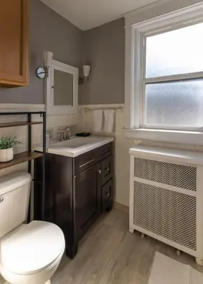 a bathroom with a toilet and a sink and a window at Hyde Park Comfort Near Rookwood in Cincinnati