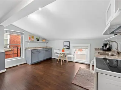 a kitchen with white cabinets and a table and a sink at Studio steps to Soccer and OTR and Downtown in Cincinnati