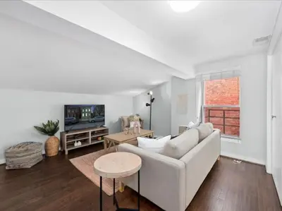 a living room with a white couch and a tv at Studio steps to Soccer and OTR and Downtown in Cincinnati