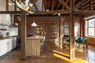 a kitchen with a table and chairs and a brick wall at Stunning Loft in the heart of OTR in Cincinnati