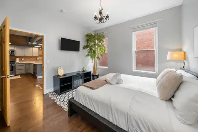 a bedroom with a large white bed and a television at City Escape 2BR Steps to TQL near OTR and Downtown in Cincinnati