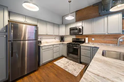 a kitchen with stainless steel appliances and wooden floors at City Escape 2BR Steps to TQL near OTR and Downtown in Cincinnati