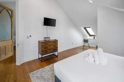 a white bedroom with a bed and a tv at Hyde Park Penthouse with Private Patio in Cincinnati