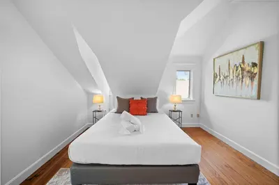 a white bedroom with a large white bed and two lamps at Hyde Park Penthouse with Private Patio in Cincinnati