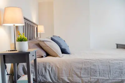 a bedroom with a bed with pillows and a table with a lamp at Gorgeous Condo in the Heart of OTR Free Parking in Cincinnati