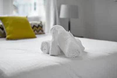 a white folded towel sitting on top of a bed at Cozy 1BR Near Zoo, UC, OTR, Downtown in Cincinnati