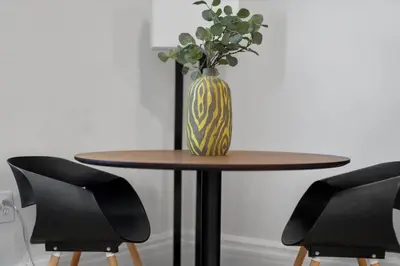 a vase sitting on top of a wooden table with chairs at Cozy 1BR Near Zoo, UC, OTR, Downtown in Cincinnati