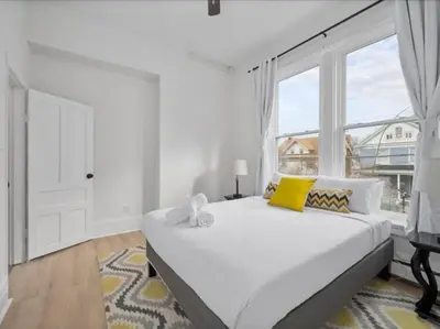 a white bedroom with a large bed and a window at Cozy 1BR Near Zoo, UC, OTR, Downtown in Cincinnati
