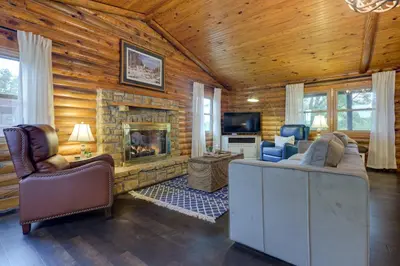a living room with a fireplace in a log cabin at Cozy Brookville Home with Fire Pit and Deck! in Brookville