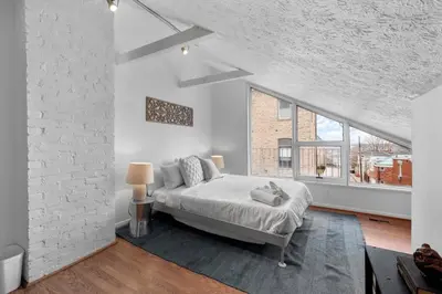 a white bedroom with a bed and a large window at Stylish Mt Adams 1BR in great location in Cincinnati