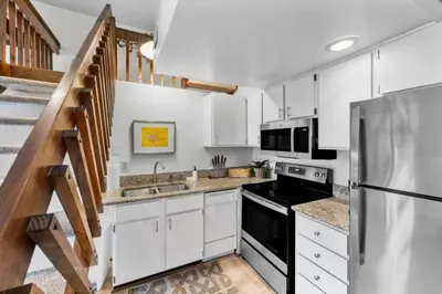 a kitchen with white cabinets and a stainless steel refrigerator at Stylish Mt Adams 1BR in great location in Cincinnati