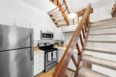 a kitchen with a stainless steel refrigerator and stairs at Charming Mt Adams 1BR in Prime Location in Cincinnati