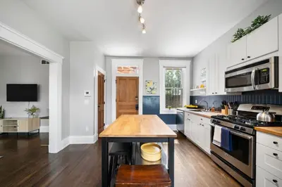 a kitchen with white cabinets and a wooden table at Walkable 2BR near Findlay Market Downtown UC in Cincinnati