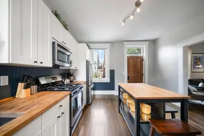 a kitchen with white cabinets and a wooden table at Walkable 2BR near Findlay Market Downtown UC in Cincinnati