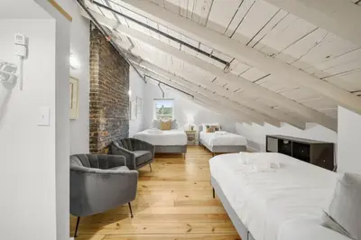 a room with two beds and chairs and a brick wall at Huge Retrea w Rooftop Deck Stay At Farmers Market in Cincinnati