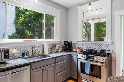 a kitchen with a stove and a sink and two windows at Modern Oakley Retreat - King Bed - Free Parking - Centrally Located in Cincinnati