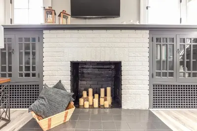 a white brick fireplace with a bunch of candles at The 1920’s Dutch Colonial - Highland Square in Akron