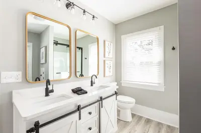 a bathroom with a sink and a toilet and two mirrors at The 1920’s Dutch Colonial - Highland Square in Akron