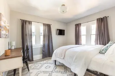 a bedroom with a bed and a desk and windows at The 1920’s Dutch Colonial - Highland Square in Akron