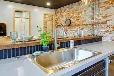 a kitchen with a sink and a brick wall at Downtown Millersburg Retreat with Sleek Interior! in Millersburg