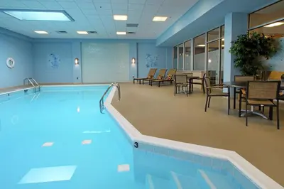 a swimming pool in a room with chairs and tables at Doubletree by Hilton Newark in Newark