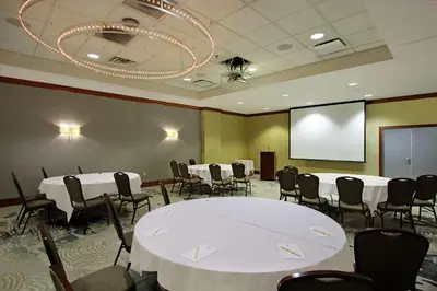 a conference room with tables and chairs and a projection screen at Doubletree by Hilton Newark in Newark