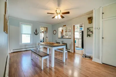 a living room with a table and a ceiling fan at Downtown Russells Point Cottage Near Indian Lake! in Russells Point